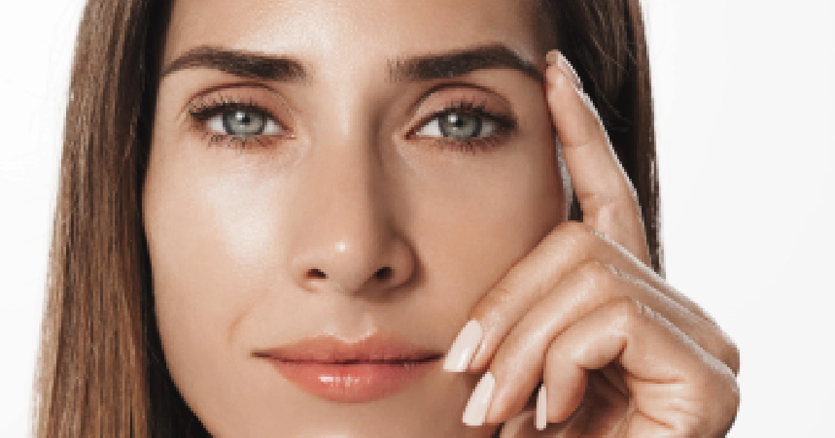 Close-up of a woman with brown hair, blue-green eyes, and clear skin, touching her temple, promoting SKINVIVE™ Injectable Treatment in Chicago, IL.